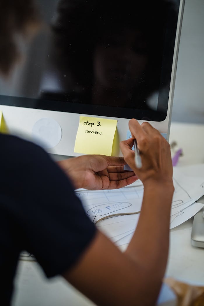 Close-up of a woman writing on sticky notes in an office setting.